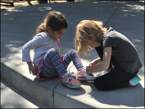 child tying another child's shoe